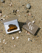 Tiger’s Eye gua sha facial massage tool for sculpting and skincare inside of the brown storage box